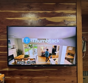 A television displaying a home interior with a dining area, kitchen, and living space.