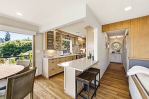 Une cuisine moderne dotée d’un îlot central, de meubles en bois et offrant une vue sur l’extérieur.