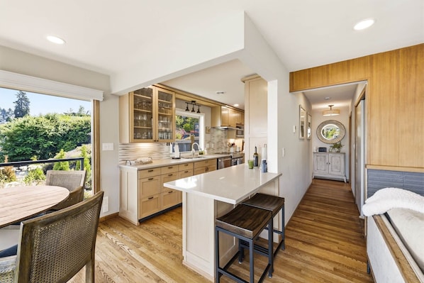 A modern kitchen with a central island, wooden cabinets, and a view of the outdoors. - Luxury Waterfront Home walk to Downtown Gig Harbor (Gig Harbor)