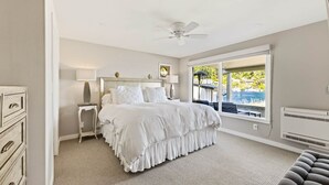 A bedroom with a bed, bedside tables, a ceiling fan, and a view of a body of water. - Luxury Waterfront Home walk to Downtown Gig Harbor (Gig Harbor)