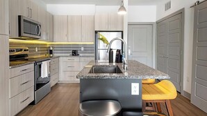 Eine moderne Küche mit Edelstahlgeräten, einer Arbeitsplatte aus Granit und Holzschränken.