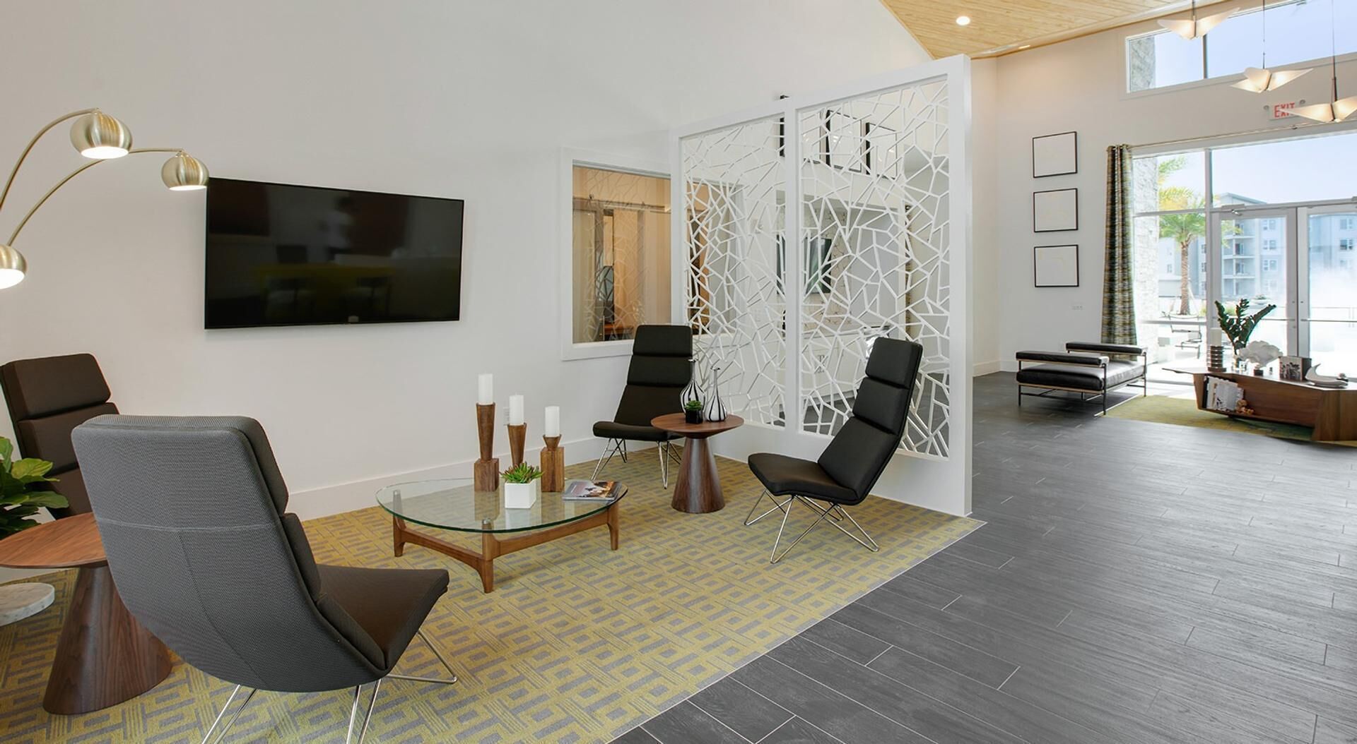 A modern hotel lobby with a flat-screen TV, seating areas, and a decorative partition.