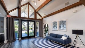 Ein geräumiges Wohnzimmer mit einem großen Sofa, einem blau-weiß gestreiften Teppich und einer modernen Lampe.