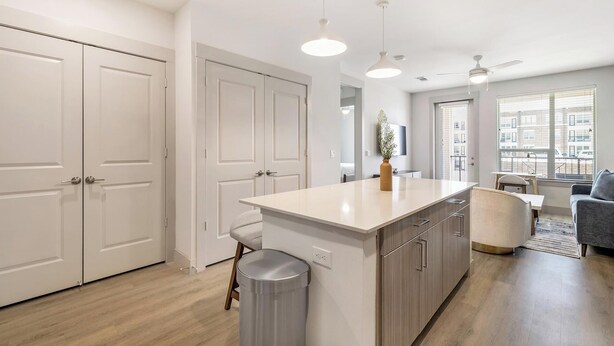A modern kitchen with a central island, white cabinetry, and a view to the outside. - Landing | Modern 1BD, Rooftop Lounge, Gym (Frisco)