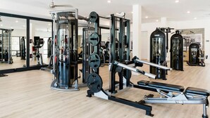 A gym with various exercise machines, mirrors, and a wooden floor. - Landing | Amazing 1BD, Gym, Rooftop Lounge (Frisco)
