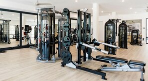 Ein Fitnessstudio mit verschiedenen Trainingsgeräten, Spiegeln und Holzboden.