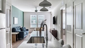 Een moderne keuken met een centraal eiland, een zithoek met een bank en een aan de muur bevestigde televisie.