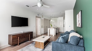 Een moderne woonkamer met een flatscreen televisie, een houten console en een blauwe bank.