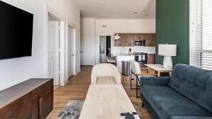 Eine moderne Wohnung mit Wohnzimmer, Essbereich, Küchenzeile und einem an der Wand befestigten Fernseher.