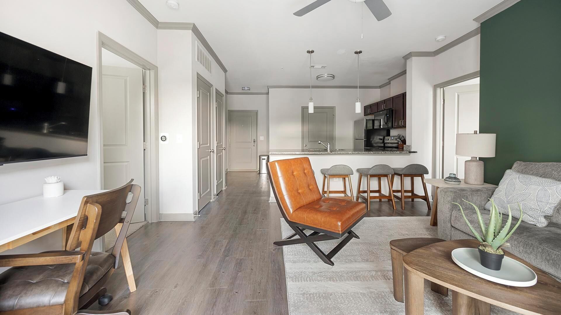 Ein modernes Wohnzimmer mit Ledersessel, Sofa und Essbereich mit Holzsesseln.
