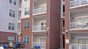A multi-story residential building with a swimming pool and outdoor seating area. - Landing | Beautiful 2BD, Gym, Pool (Nashville)