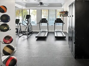 Ein Fitnessraum mit Laufbändern, Crosstrainern und verschiedenen Übungsbällen.
