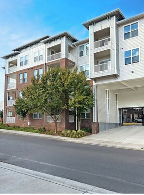 A multi-story residential building with balconies, brick facade, and a gated driveway. - Landing | Incredible 2BD, Pool, Clubhouse (Nashville)