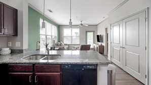 Uma cozinha moderna com bancadas de granito, lava-louças e um espaço de jantar com sofá e mesa.