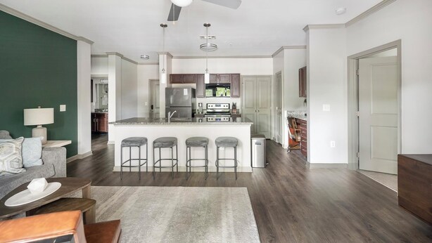 A modern kitchen with a central island, bar stools, and a dining area with a table and chairs. - Landing | Modern 2BD, Pool, Gym (Nashville)