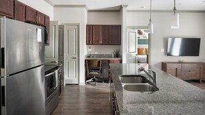 A modern kitchen with stainless steel appliances, a granite countertop, and a built-in oven. - Landing | Modern 2BD, Pool, Gym (Nashville)