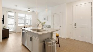 Una cocina moderna con una isla central, un ventilador de techo y vistas al exterior.