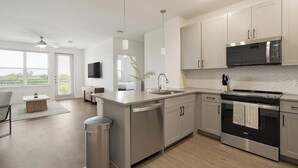 A modern kitchen with stainless steel appliances, a herringbone tile backsplash, and a large window providing natural light. - Landing | Spectacular 1BD, Courtyard, Pool (Dallas)