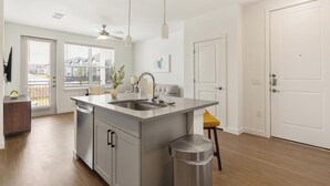 Una cocina moderna con una isla central, electrodomésticos de acero inoxidable y vistas al exterior.