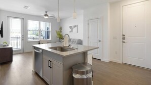 A modern kitchen with a central island, a dishwasher, and a trash can. - Landing | Chic 1BD, Pool, Gym (Dallas)