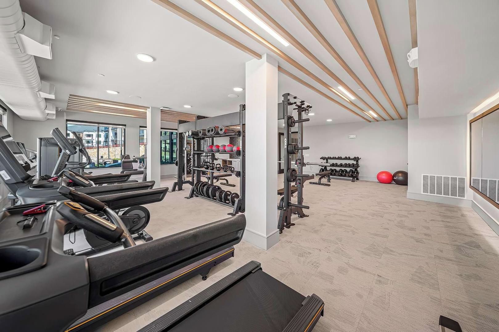 Ein Fitnessraum mit Laufbändern, Gewichten und Übungsbällen.