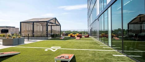 A modern building with a sports field, seating areas, and a wooden structure.