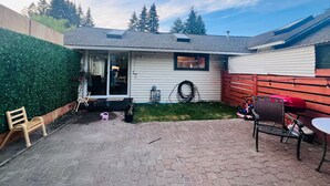 A single-story house with a patio area, a sliding glass door, a small garden, and a red fence.