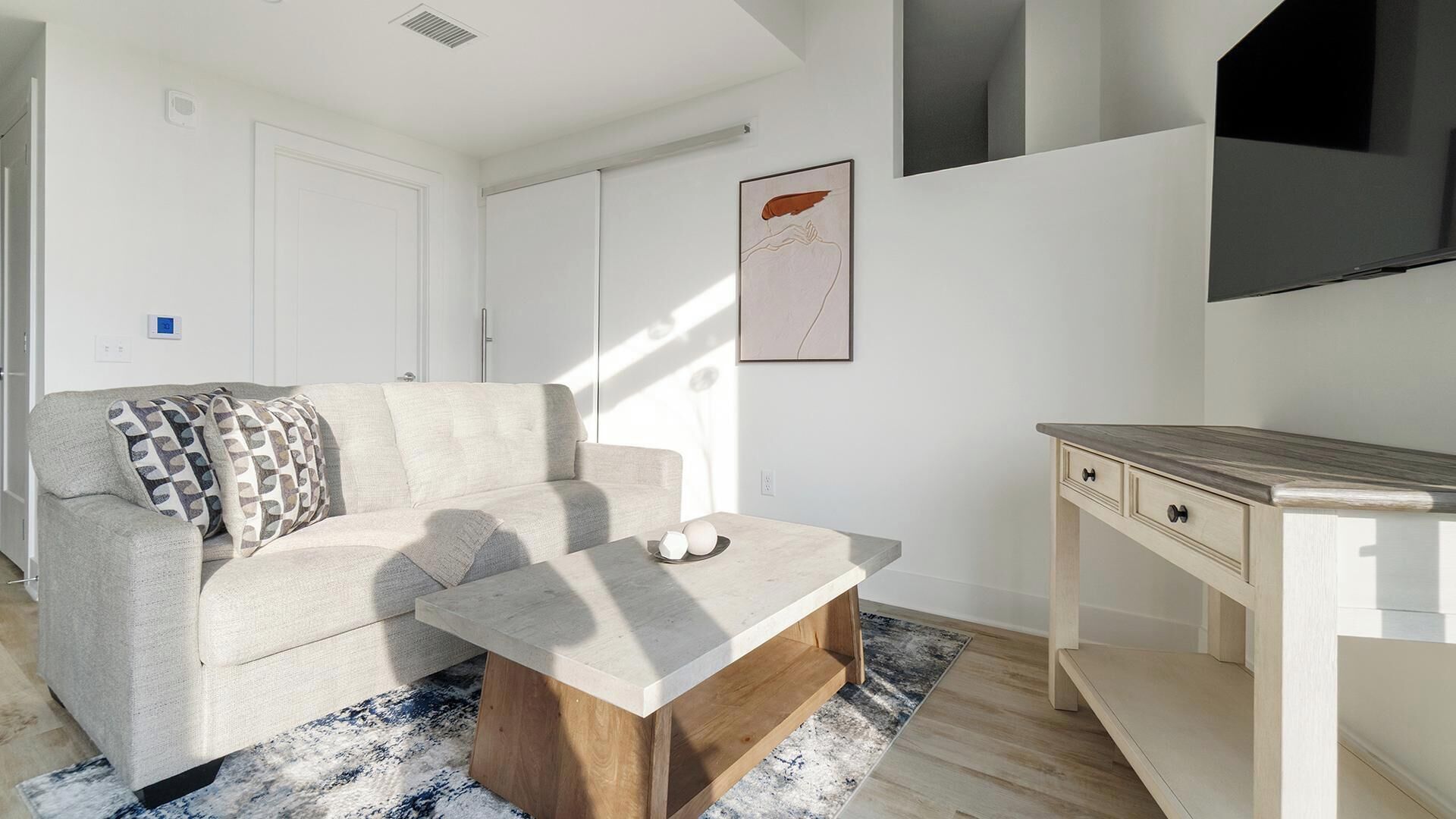 A modern living room with a sofa, coffee table, and a TV stand.