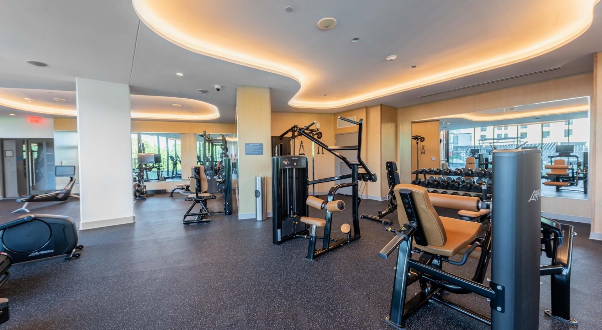 A gym with exercise equipment, large windows, and a curved ceiling design.