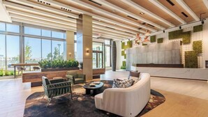 A modern lobby with a high ceiling, large windows, and a seating area with a sofa and chairs. - Landing | Incredible Studio in Caraleigh (Raleigh)