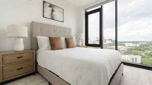 Un dormitorio con una cama grande, dos mesitas de noche, vistas a la ciudad y un diseño moderno.