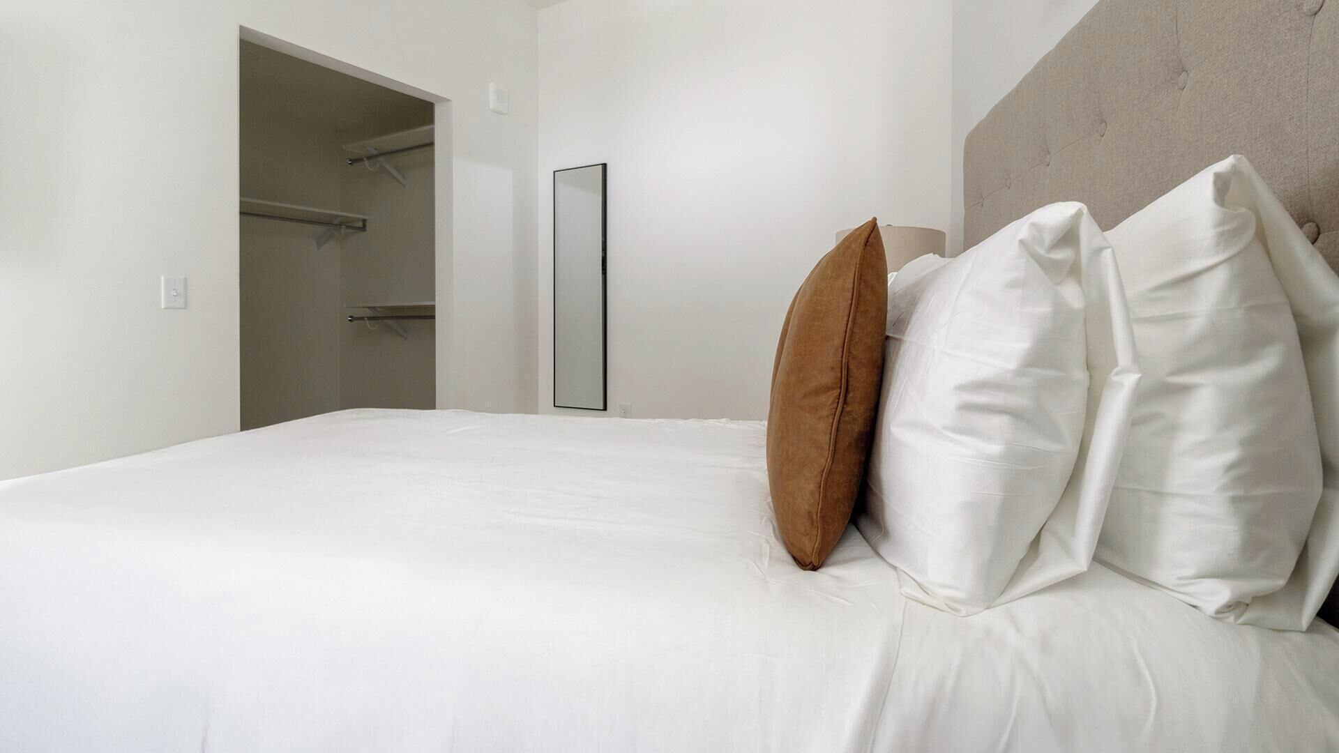 Une chambre d’hôtel avec un lit, un oreiller marron et un oreiller blanc.