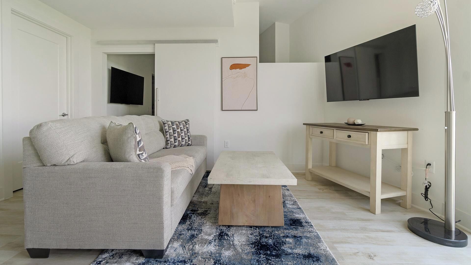 Una sala de estar moderna con un sofá, una mesa de centro y un televisor montado en la pared.