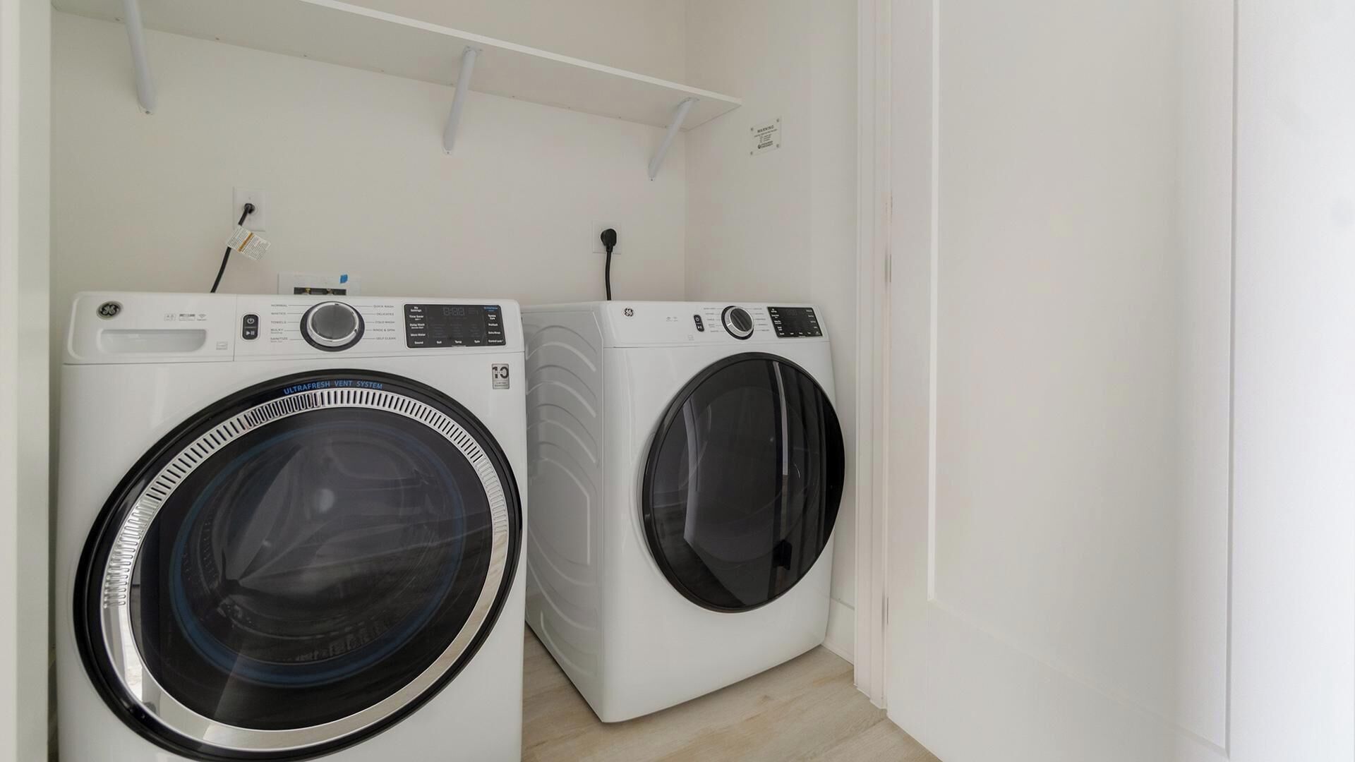 A laundry room with two front-loading washing machines and a white wall.