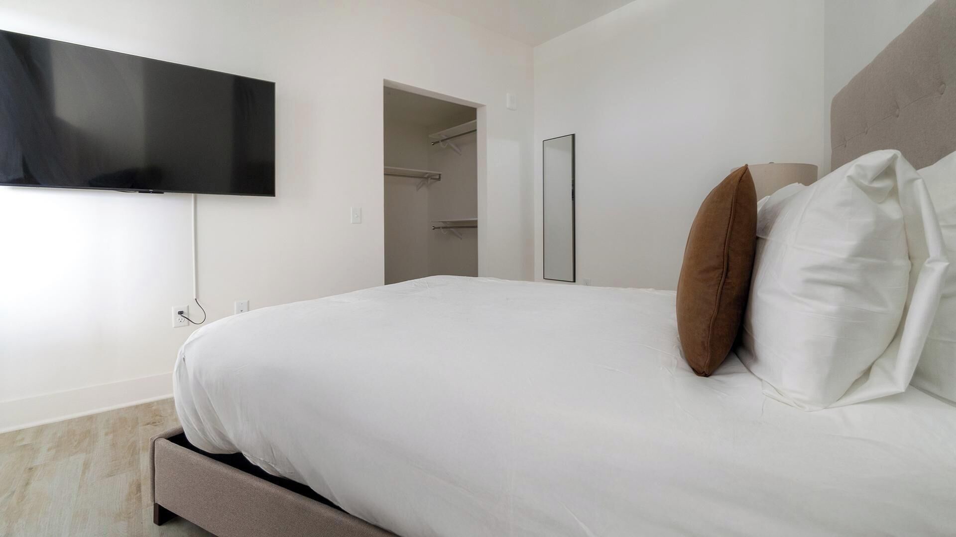 Una habitación de hotel con una cama, un televisor en la pared y un espejo.