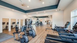 Et rummeligt fitnesscenter med varieret cardio- og styrketræningsudstyr, herunder løbebånd og vægtmaskiner.