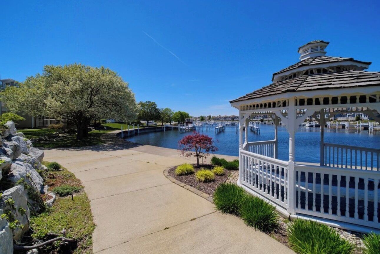 A gazebo by a lake with a clear sky.