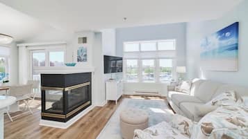 A modern living room with a fireplace, a sofa, a coffee table, and a large window.