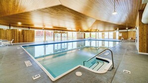 An indoor swimming pool with wooden walls and ceiling, clear pool area, and a lifeguard chair. - Cozy 1-bedroom Pet Friendly Condo in Manistee.   Pool, Hot tub, 5 min to Beach! (Manistee)
