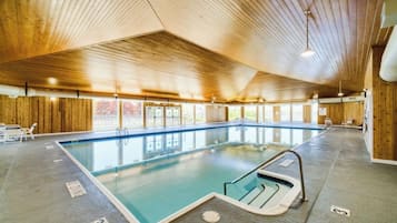 An indoor swimming pool with wooden walls and ceiling, clear pool area, and a lifeguard chair.