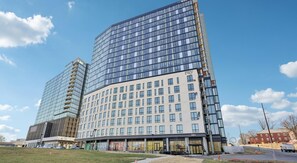 A modern hotel with a curved glass facade, multiple floors, and a flat roof. - Landing | Modern Studio in Caraleigh (Raleigh)