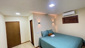 A bedroom with a bed, a door, an air conditioning unit, and wall-mounted lights.