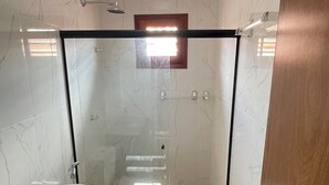Un bagno moderno con box doccia in vetro, un water e un lavandino.