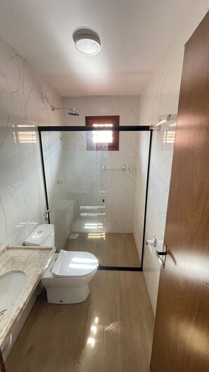 A modern bathroom with a glass shower enclosure, a toilet, and a sink.