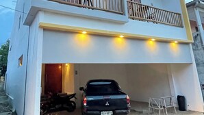 A two-story building with a balcony, a parked truck, and a motorcycle.