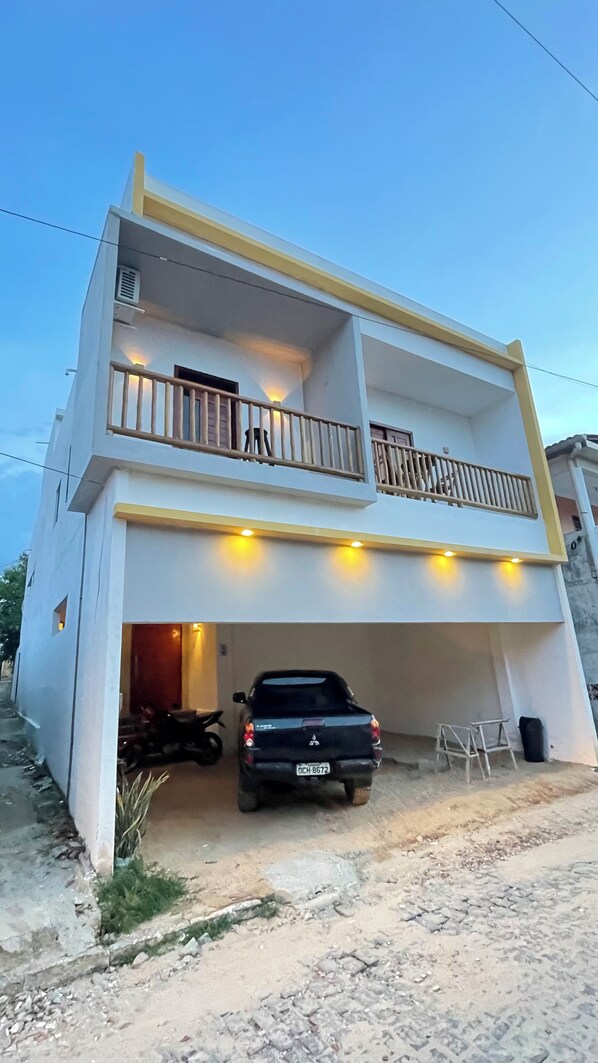 A two-story building with a balcony, a parked truck, and a motorcycle.