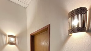 A hallway with a wooden door, a textured wall, and a wall-mounted light fixture.