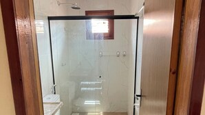 A bathroom with a toilet, a shower, and a glass door.