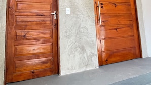 Two wooden doors with a textured wall and a concrete floor.