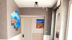 A hallway with a tiled floor, a door, and two framed pictures on the walls. - Terrazza Cristallini Napoli (Naples)